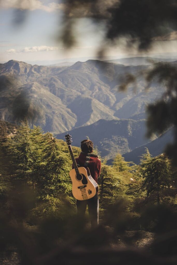 A guitarist stands in awe of the mountain scenery in Algeria, capturing the essence of nature and music.